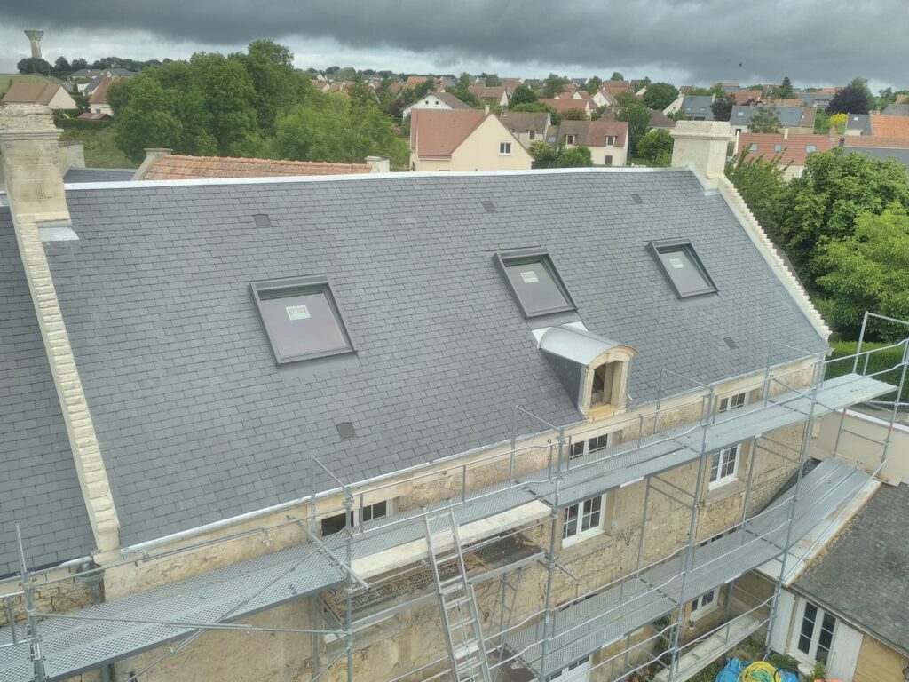 Vue en hauteur de l'ensemble de la toiture d'une bâtisse traditionnelle de la région de Bayeux. après rénovation de la couverture en ardoises.